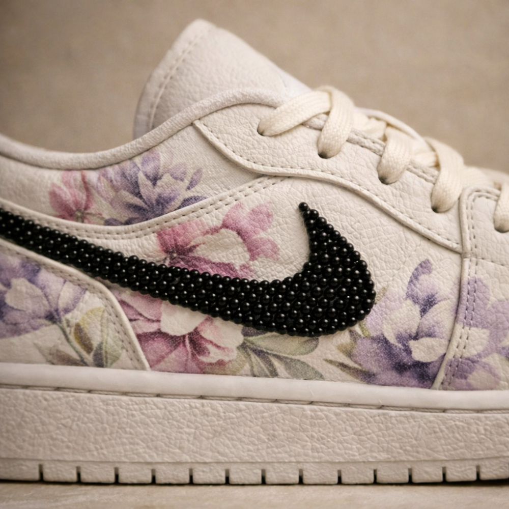 White sneaker with floral pattern and black rhinestone Nike logo on a neutral background