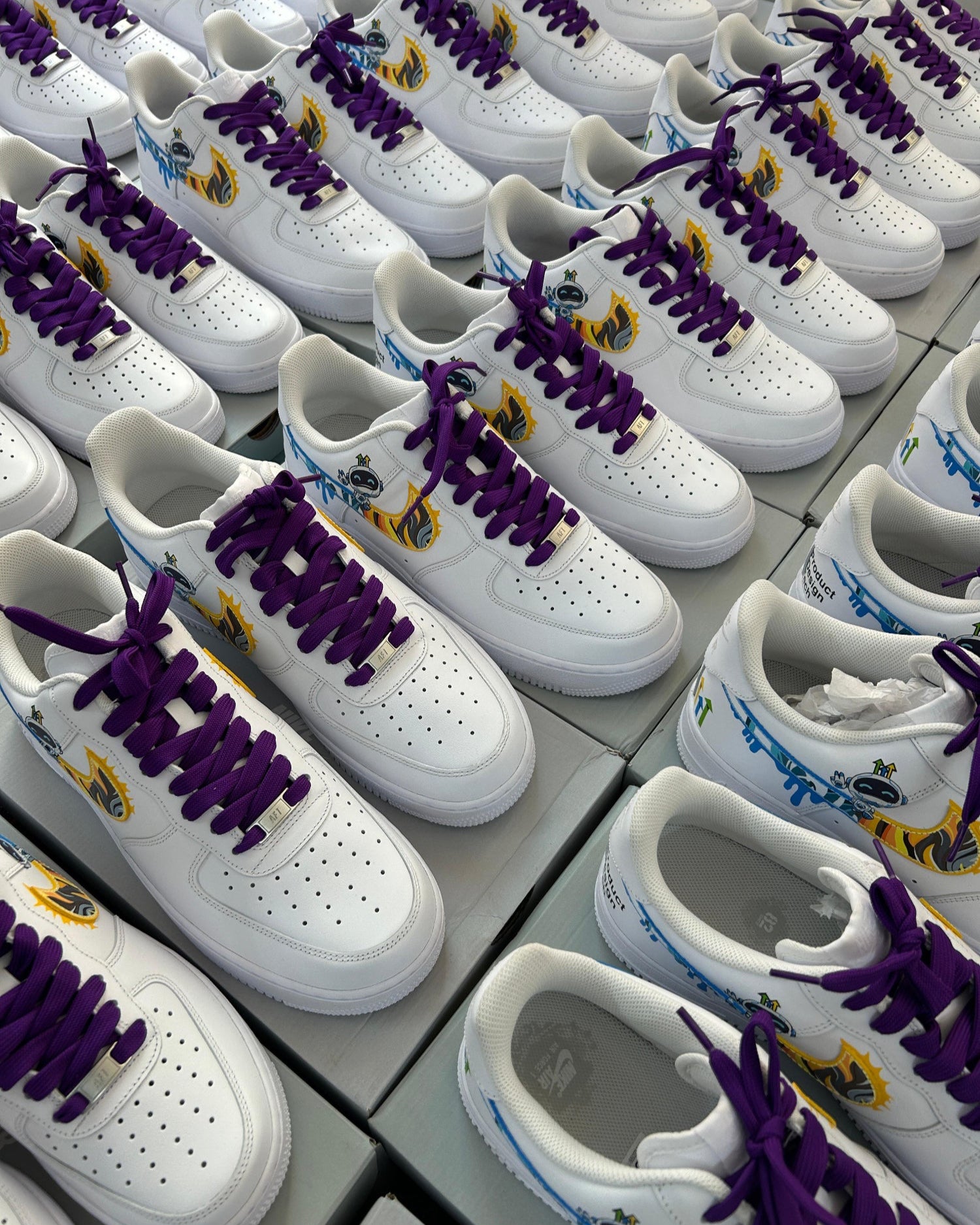 White sneakers with purple laces and logos on a gray surface