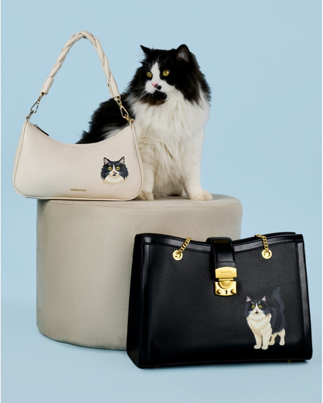 Handbags with cat designs and a cat sitting on a box against a light blue background, featuring the brand 'Miraggio'.