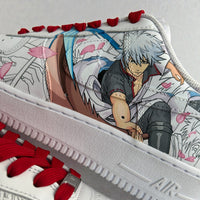 Close-up detail of custom hand-painted Nike Air Force 1 sneakers featuring anime character illustration layered over manga line art, accented with red laces, cherry blossom elements, and fine brushwork on premium white leather.