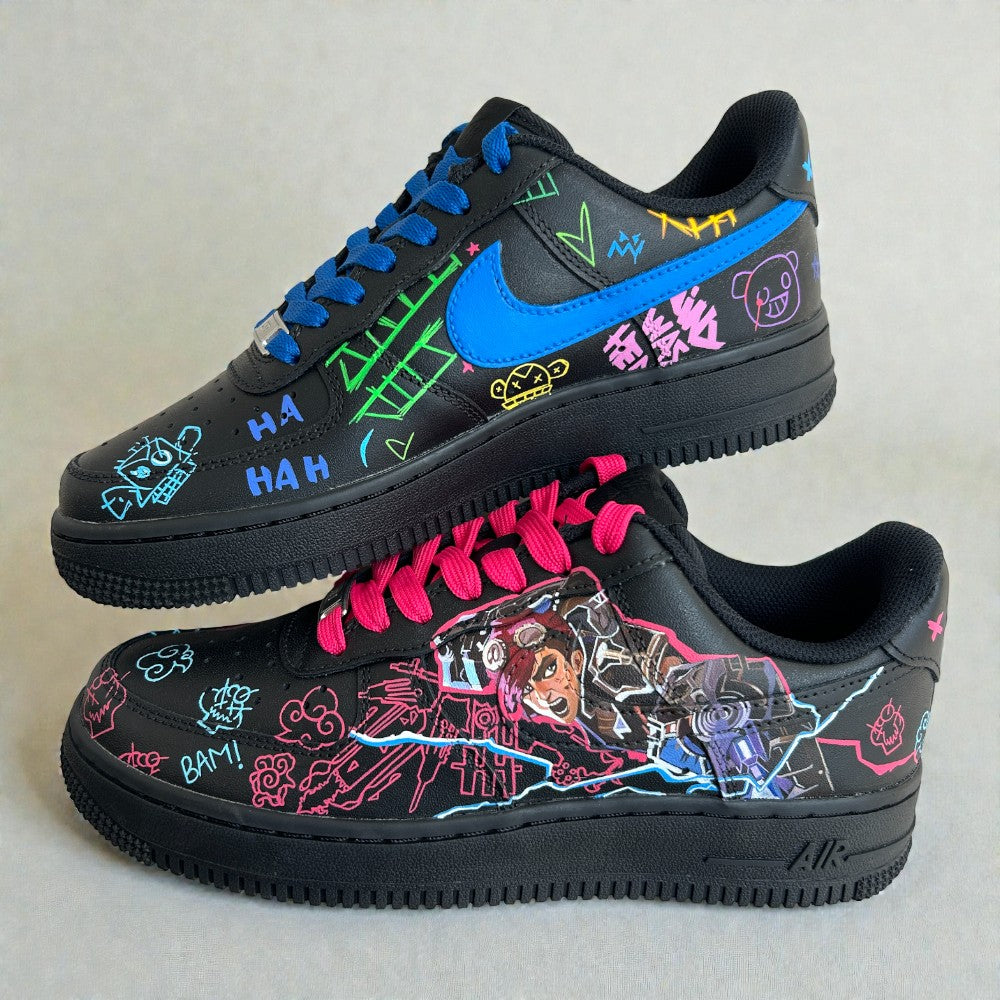 Pair of custom Nike Air Force 1 sneakers inspired by Jinx from Arcane, featuring hand-painted character artwork, neon graffiti illustrations, electric blue swoosh, and mismatched pink and blue laces on a black leather base.