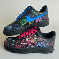 Pair of custom Nike Air Force 1 sneakers inspired by Jinx from Arcane, featuring hand-painted character artwork, neon graffiti illustrations, electric blue swoosh, and mismatched pink and blue laces on a black leather base.