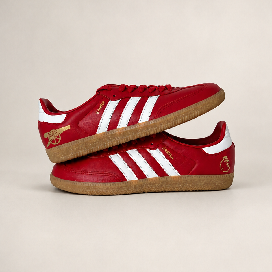A pair of red low-top Adidas red samba sneakers stacked on top of each other, featuring Arsenal icons. 