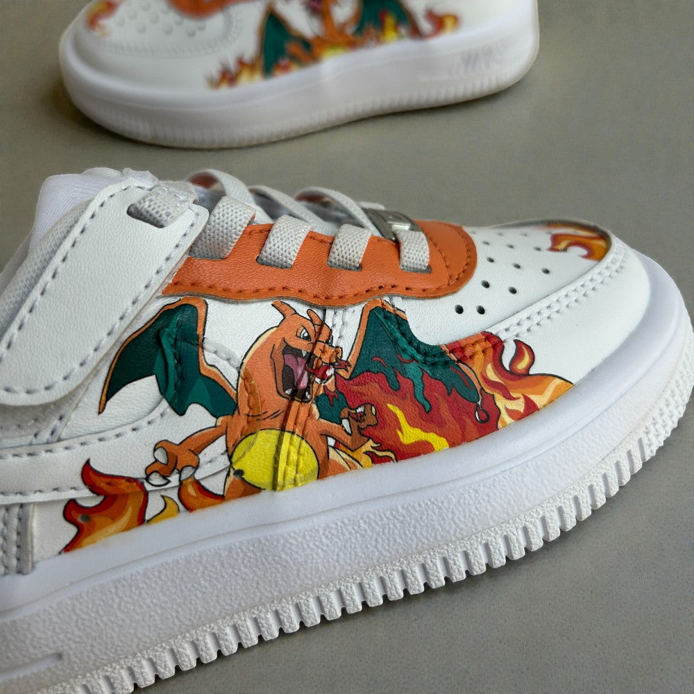 Close-up detail of a custom hand-painted kids Nike Air Force 1 sneaker showing a fire-breathing dragon illustration, layered flame details, orange leather accents, and textured white sole.