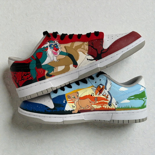 Custom hand-painted Nike Dunk Low sneakers inspired by Disney’s The Lion King, featuring detailed illustrations of Simba, Rafiki, and Zazu across both shoes, painted by hand on premium leather and photographed in a stacked side profile.