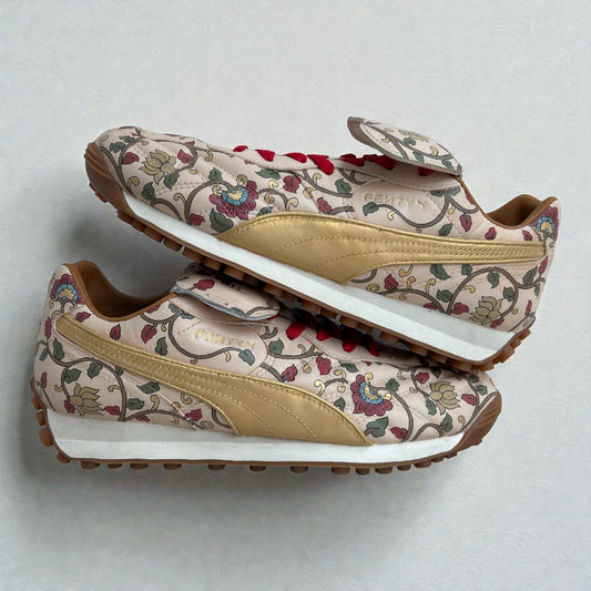 Custom hand-painted Puma sneakers featuring intricate floral artwork inspired by Indian motifs, with metallic gold side panels and red laces, painted by hand on a neutral base and photographed in a stacked side profile.