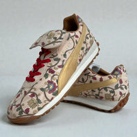 Custom hand-painted Puma sneakers featuring intricate floral artwork inspired by Indian motifs, metallic gold side panels, red laces, and premium leather detailing, photographed as an angled pair on a clean neutral background.