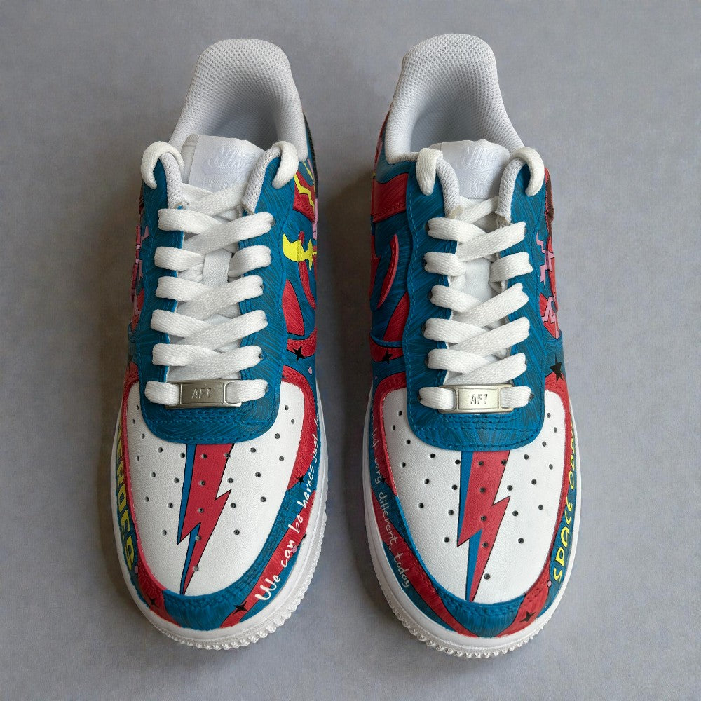 Top view of custom hand-painted Nike Air Force 1 sneakers inspired by David Bowie, featuring iconic lightning bolt motif on the toe box, red and blue graphic panels, white laces, and Space Oddity themed detailing on white leather.