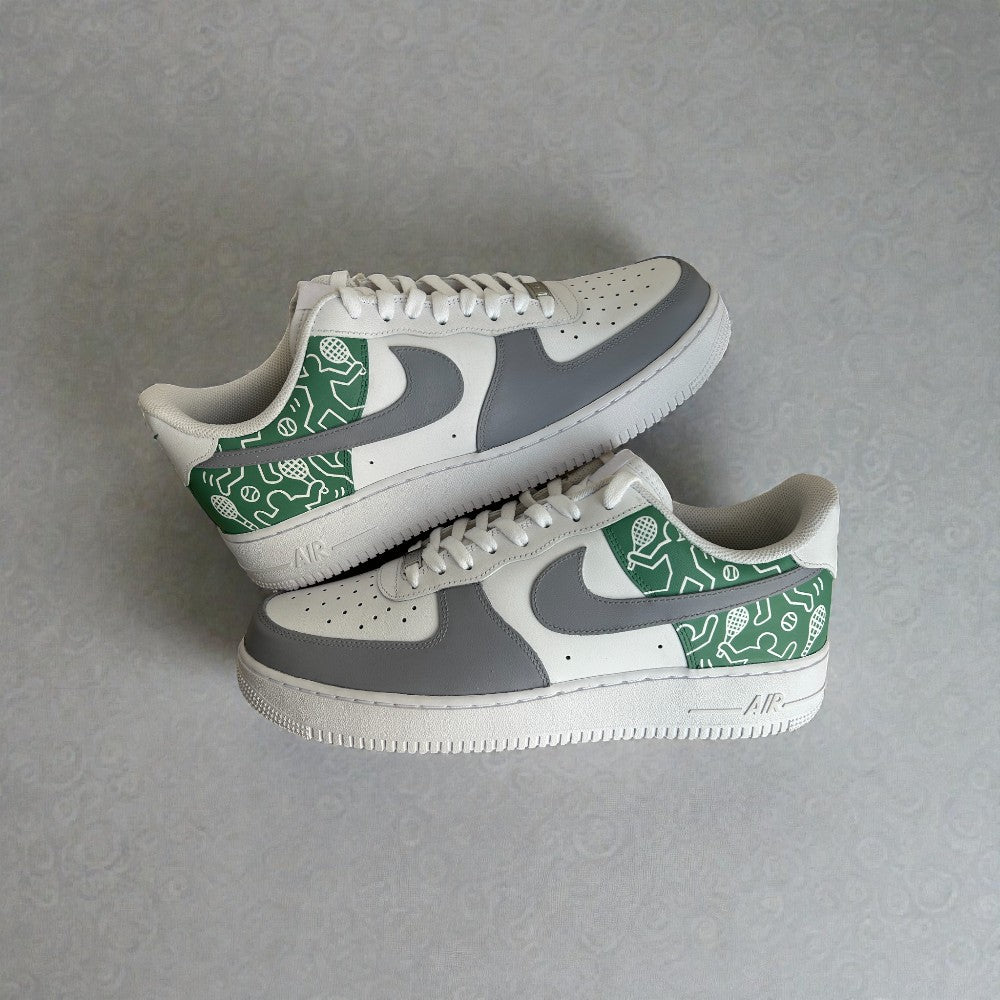 Side view of custom Nike Air Force 1 sneakers featuring grey and white leather panels with a green illustrated heel and quarter design, hand-painted detailing, white laces, and classic AF1 silhouette.