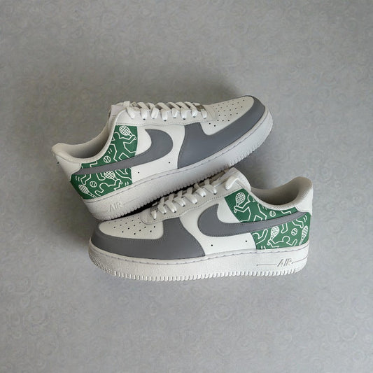 Side view of custom Nike Air Force 1 sneakers featuring grey and white leather panels with a green illustrated heel and quarter design, hand-painted detailing, white laces, and classic AF1 silhouette.