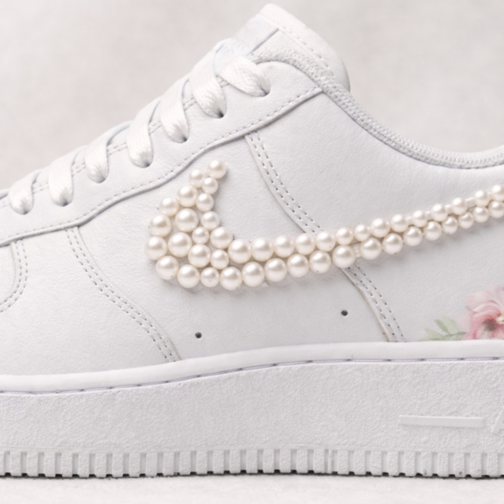 White sneaker with pearl embellishments on the Nike logo against a light background