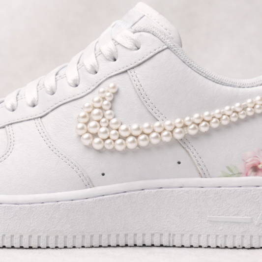 White sneaker with pearl embellishments on the Nike logo against a light background