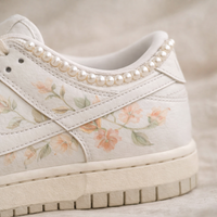 Floral-patterned sneaker with pearl embellishments on a neutral background
