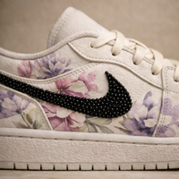White sneaker with floral pattern and black rhinestone Nike logo on a neutral background