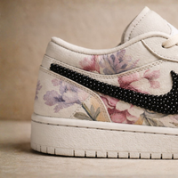 Floral-patterned sneaker with black speckled swoosh logo on a beige background