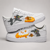 A pair of white Nike Air Force 1 Low sneakers featuring custom cartoon graphics of Tom and Jerry on the sides, displayed against a neutral light gray background.